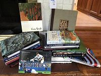 Coffee table books stacked on a wooden table, titles visible including Van Gogh, Life's Picture History of World War II, New York Yankees 365, and assorted baseball and art books