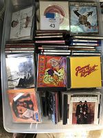 Photo of plastic container with multiple assorted CDs including rock, opera, Latin, Motown genres.