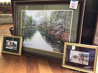 Three framed Charleston scene artworks displayed on floor against wall. One large and two smaller pieces.