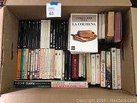 Box containing approximately 42 Spanish language novels, including classics and contemporary literature in paperback and hardcover.