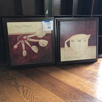 Both framed prints shown side by side, placed on wooden floor.