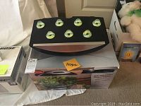 Front view of AeroGarden Pro 100 with seed pods on top, resting on its original box.