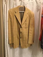 Full front view of the vintage Ermenegildo Zegna double breasted silk jacket in tan hanging on a hanger