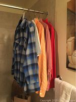 Six men's shirts hanging, includes a blue plaid Pendleton long sleeve shirt and other colored shirts