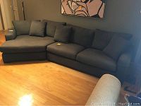 Full view of dark gray L-shaped sectional sofa in living space