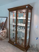 Front view of wood framed china cabinet with glass doors showing shelves filled with glassware.