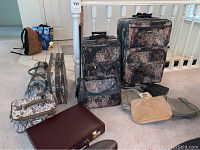 Wide photo showing seven bags including Jaguar floral pattern suitcases, briefcases and handbags along with other assorted bags on a carpeted floor