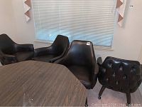 Four black swivel tufted dining chairs around a wooden table in a room with blinds.