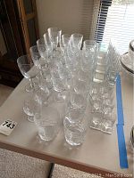 Wide angle shot of the entire crystal and cut glass stemware set arranged on a table, showing glasses in several rows including tumblers, goblets, and wine glasses.