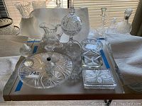 Full set of 13 cut glass items shown together on display board, including pitcher, cake plate, ashtrays, decorative pieces, and candlesticks.