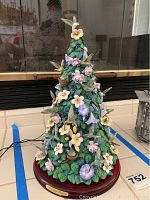 Full view of Bradford Editions' illuminated ceramic hummingbird tree sculpture featuring green leaves, pastel flowers, and hummingbirds, mounted on a wooden base.
