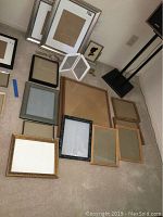 Overview of all frames showing variety in size, color, and material laying on carpeted floor.