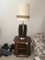 End table and vintage lamp shown together, lamp on table, including part of floral sofa and other miscellaneous items displaced.