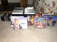 Multiple compact discs in jewel cases with visible artists and album covers, including Kenny Rogers and compilation albums.