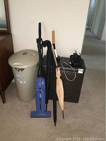 Photo showing Eureka vacuum, two hampers, two umbrellas, and cordless phone items grouped together.