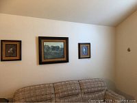 Three framed wall art pieces hung above couch; two smaller ones flank a larger center piece
