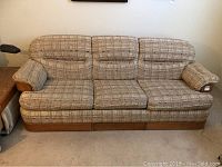 Full front view of the three-seat Bassett upholstered sleeper sofa with patterned fabric and wooden base.