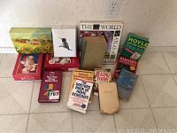 Photo of lot displaying various books including health, dictionary, and games books alongside greeting cards.