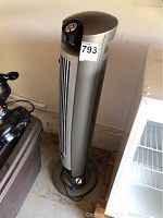 Full view of the Lasko portable tower fan standing on a beige floor near a wall, showing the overall height and design.