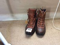 Pair of brown Carhartt men's boots with lace-up design, shown from front angle on carpeted floor.