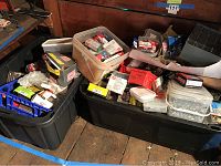 Plastic bins and cardboard boxes filled with numerous small packages of assorted nails, screws, washers, and bolts.
