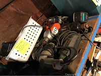 Photo showing multiple electric and battery powered drills piled together, various brands visible including Porter and Cable and Skil.