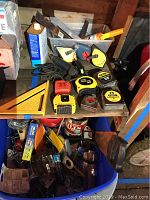 Wide view of the shelf showing multiple tape measures, squares, wrenches, chalk reels, and other hand tools.