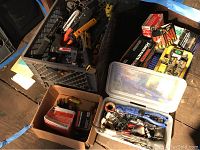 Full lot overview showing power staplers, manual stapler, boxes of fasteners, and containers with soldering tools and other accessories.