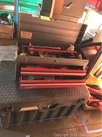 Front angle view of Craftsman toolbox with two drawers and top compartment open showing tools inside. Toolbox rests on large black storage bin.