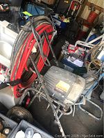 Overall view of sprayer mounted on metal cart with coiled hoses