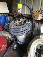 Air compressor unit with coiled hose and pressure gauges on top, showing general condition and setup.