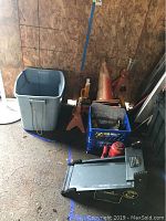 Overall view showing the 20 ton hydraulic floor jack, orange jack stands, blue plastic bin with various accessories, and traffic cones.