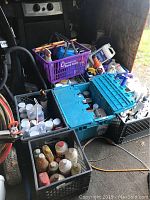 Full view of stacked crates and toolbox with bottles and cans of chemicals and fluids for painting and cleaning