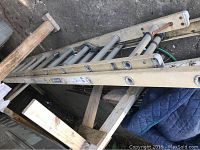 Full ladder laid on ground with supporting wooden frame visible, showing rungs and side rails