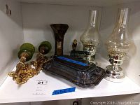 Shelf with pair of brass and green glass sconces, clear glass oil table lamps, silver plate tray, and metal boot decor.