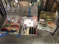 Plastic tackle boxes with fishing lures including soft plastics in packaging and various hard baits.