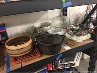 Cast iron covered pot, pottery and baking dishes on metal shelving