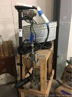 Full view of two trolling motors, one Minn Kota and one Shakespeare Wonder Troll, mounted on a wooden cart with a galvanized metal bucket and black plastic tub below.