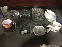 Clear glass bowls, loaf pan, souffle pan, pie plate, ceramic bowls arranged on floor beneath a chair