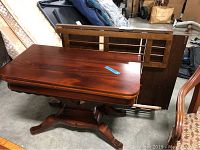 Overall view of fold top table with pedestal base and folded bookcase behind