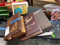 Overall view of three Bibles stacked together showing brown leather Holy Bible, Good Leader Bible, and another Bible with maroon cover.