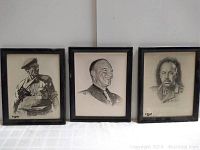 Three military portrait drawings displayed side by side on a white surface. Two on the sides are framed with black wood frames and glass; middle one is unframed.