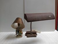 Two vintage lamps placed side by side on white background, showing one lamp with porcelain figure base and one metal desk lamp