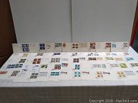 Wide view showing many first day issue envelopes with various stamps arranged on a table