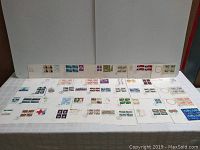 Photo showing multiple envelopes laid out horizontally, each with multiple stamps affixed and postmarked indicating day of issue dates.