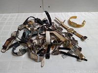 Photo showing a collection of 25 pieces including wristwatches and watch parts in mixed condition with various strap materials scattered on a white surface.