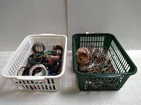 Two plastic baskets filled with assorted costume jewelry bracelets and bangles