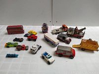 Front view of entire lot showing various diecast toy vehicles including a red double-decker bus, yellow sports car, robot figure, trucks and construction vehicles.