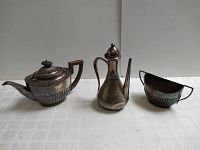 Three-piece vintage silver-plated tea set including teapot, coffee pot, and creamer.