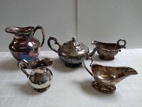 Photo showing all five vintage silverplate serving pieces on a white surface, various angles